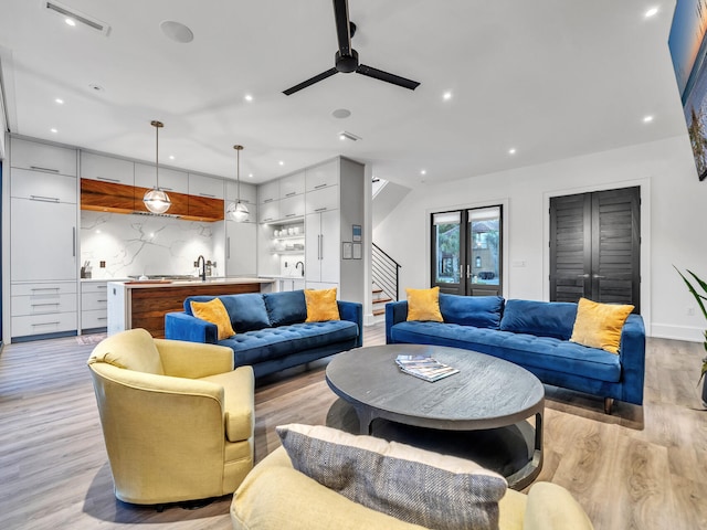 living room with light wood-type flooring, sink, and ceiling fan