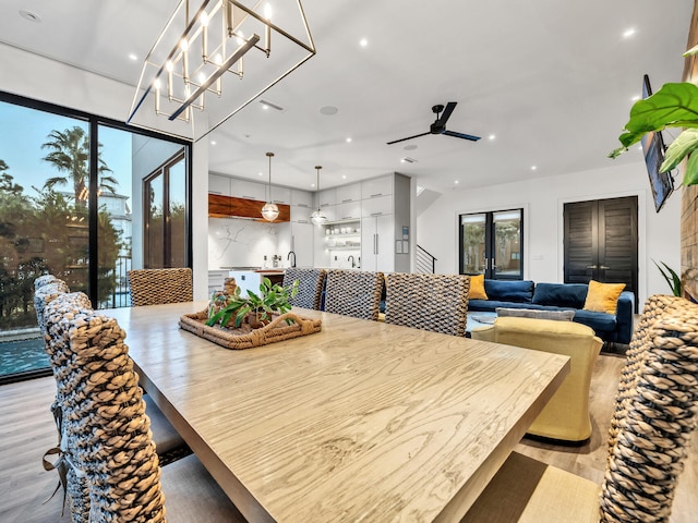 dining space with ceiling fan with notable chandelier and light hardwood / wood-style flooring