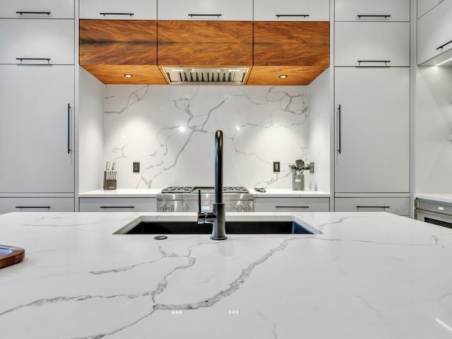 220 N Saint Francis Dr, Miramar Beach, FL 32550 - kitchen featuring modern cabinets, decorative backsplash, light stone counters, white cabinets, and exhaust hood