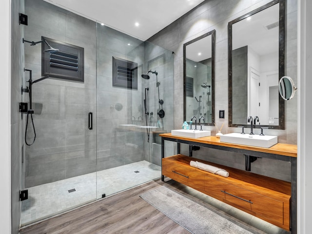 bathroom with tile walls, vanity, hardwood / wood-style floors, and an enclosed shower