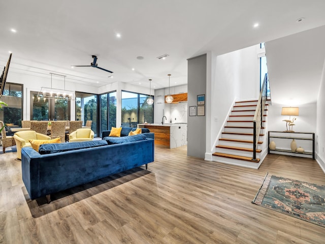 living room with light wood-type flooring, sink, and ceiling fan