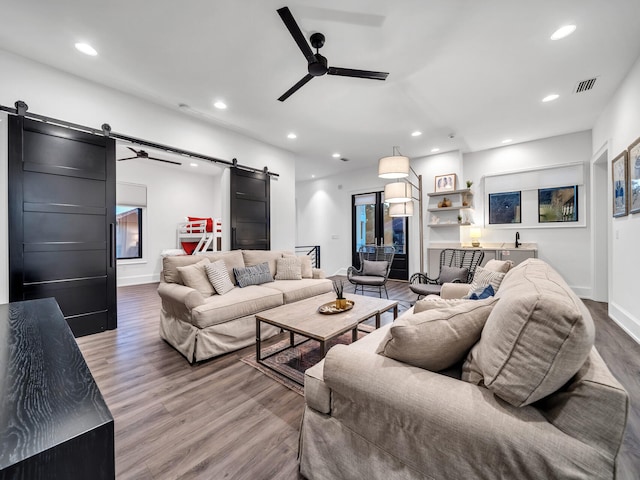 living room with ceiling fan, hardwood / wood-style flooring, and a barn door