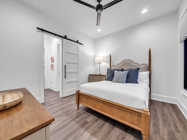 bedroom with ceiling fan, light hardwood / wood-style flooring, and a barn door