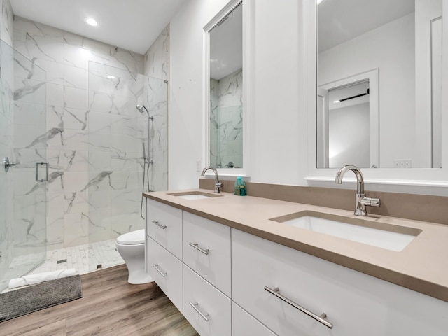 bathroom featuring toilet, vanity, hardwood / wood-style floors, and a shower with door