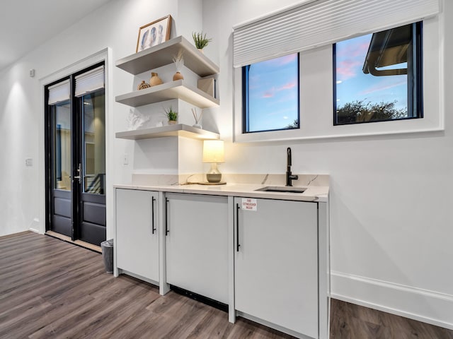 bar featuring dark hardwood / wood-style flooring, white cabinets, and sink