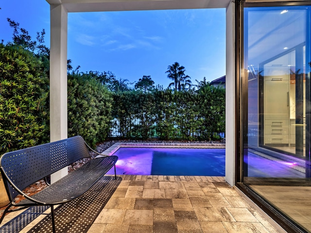 pool at dusk featuring a patio