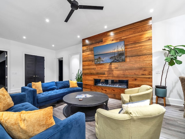 living room with ceiling fan, wooden walls, and hardwood / wood-style floors