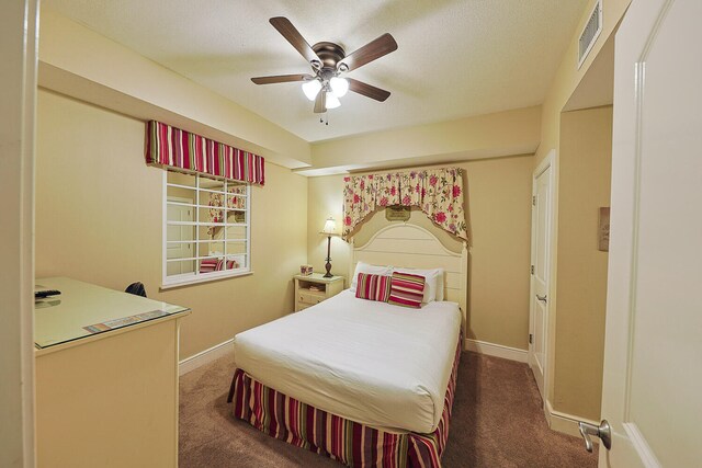 bedroom with dark colored carpet, a textured ceiling, and ceiling fan