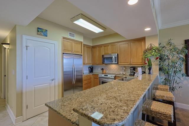 kitchen featuring sink, kitchen peninsula, a kitchen breakfast bar, stainless steel appliances, and light stone counters