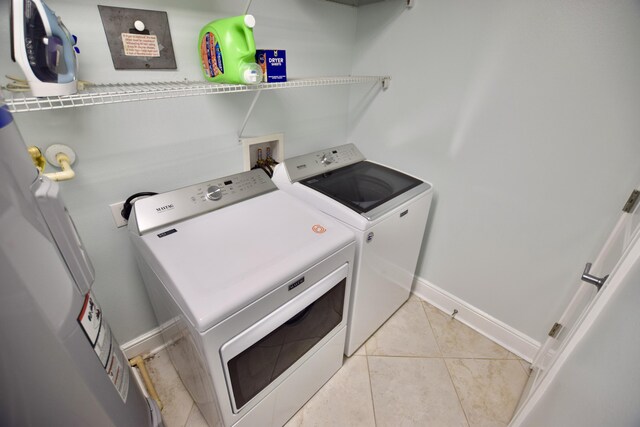 1150 Santa Rosa Blvd Unit 117, Fort Walton Beach, FL 32548 - laundry room with washing machine and clothes dryer, water heater, light tile patterned floors, and baseboards