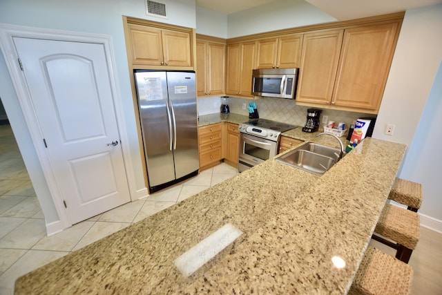 1150 Santa Rosa Blvd Unit 117, Fort Walton Beach, FL 32548 - kitchen with appliances with stainless steel finishes, a sink, tasteful backsplash, a breakfast bar area, and light tile patterned flooring
