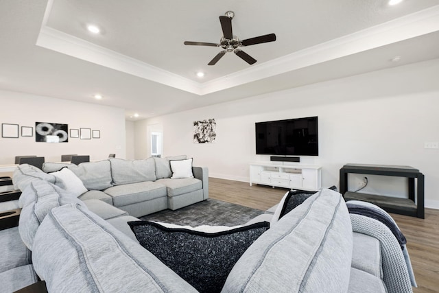 living room with a raised ceiling, crown molding, dark hardwood / wood-style floors, and ceiling fan