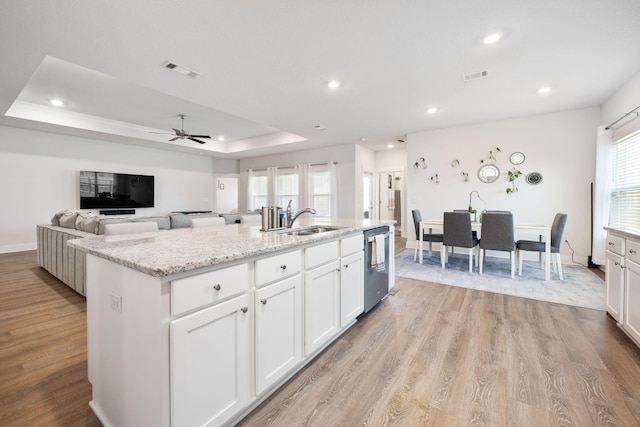 kitchen featuring a center island with sink, white cabinetry, ceiling fan, and light hardwood / wood-style flooring