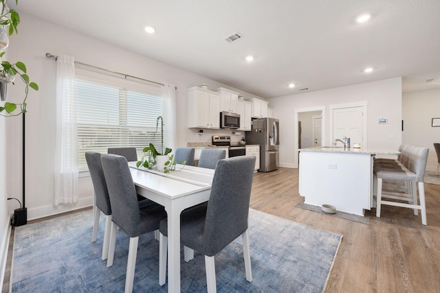 dining space with light wood-type flooring and sink