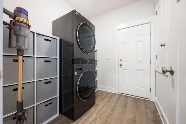 washroom with stacked washer and dryer and light hardwood / wood-style flooring