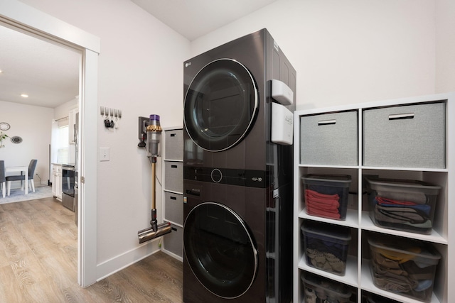 laundry room with wood-type flooring and stacked washer and dryer