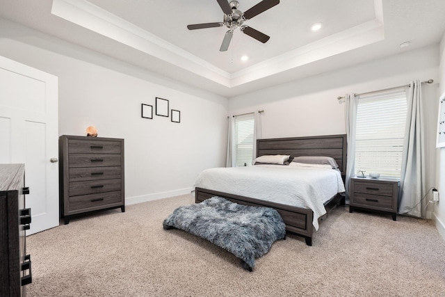 carpeted bedroom with ceiling fan and a tray ceiling