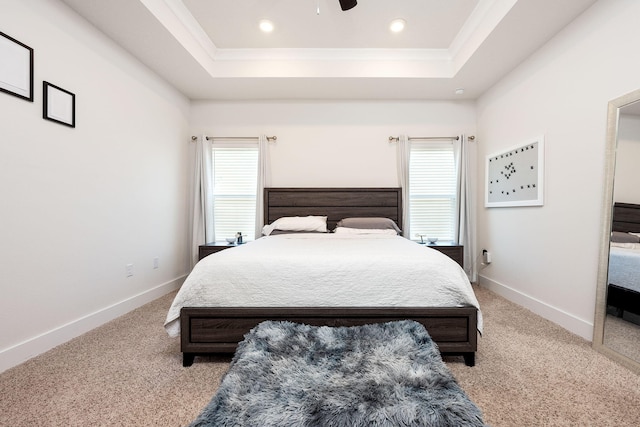 bedroom featuring light carpet, a raised ceiling, multiple windows, and ceiling fan