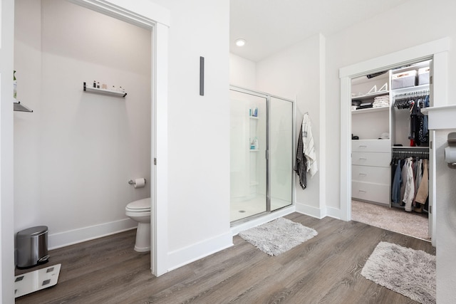 bathroom with hardwood / wood-style flooring, toilet, and an enclosed shower