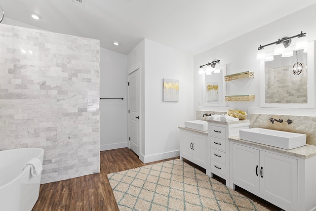 bathroom featuring tile walls, hardwood / wood-style flooring, vanity, and a bathtub