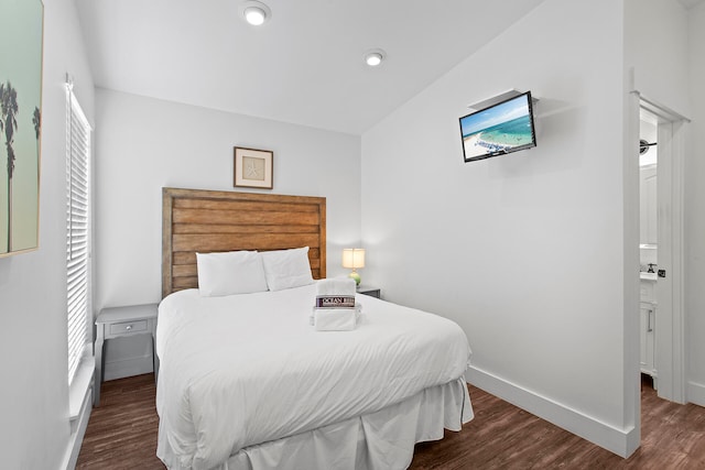 bedroom with connected bathroom, vaulted ceiling, and dark hardwood / wood-style floors