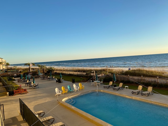 view of swimming pool featuring a view of the beach, a water view, and a patio area