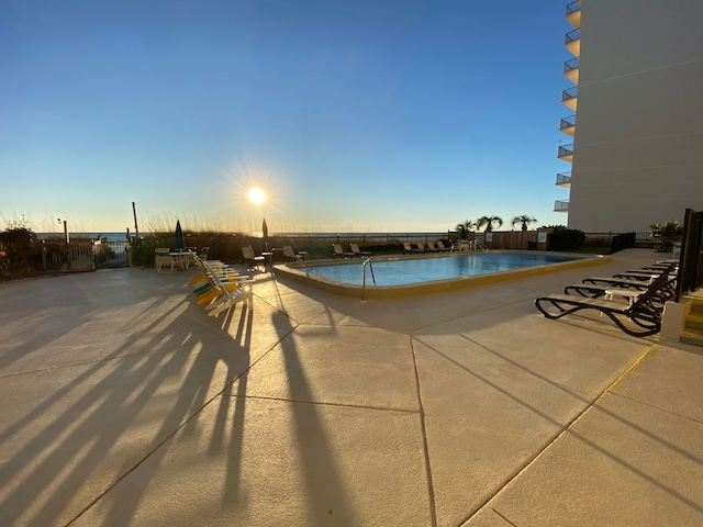 pool at dusk with a patio area