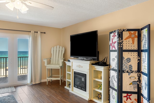 living room featuring ceiling fan, a textured ceiling, and dark hardwood / wood-style flooring