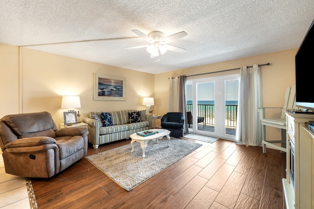 living room featuring ceiling fan, hardwood / wood-style floors, and a textured ceiling