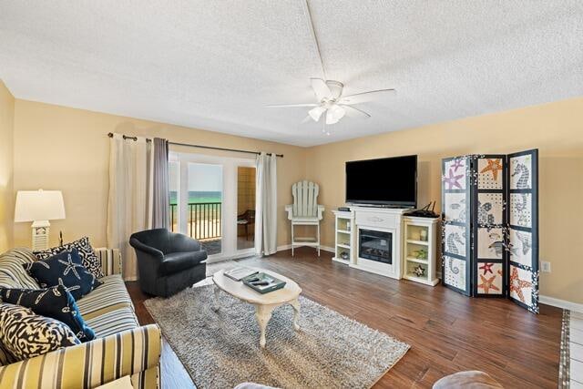 living room with ceiling fan, a textured ceiling, and dark hardwood / wood-style flooring