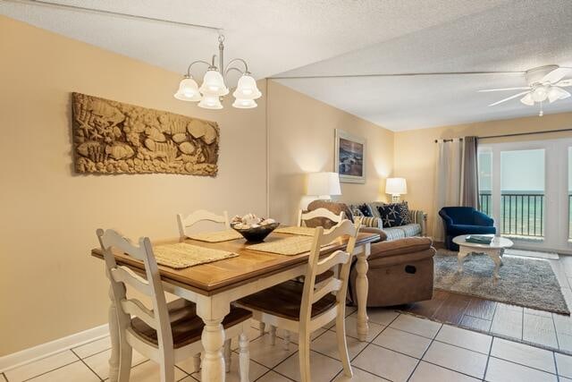 dining area with light tile patterned flooring, ceiling fan with notable chandelier, and a textured ceiling