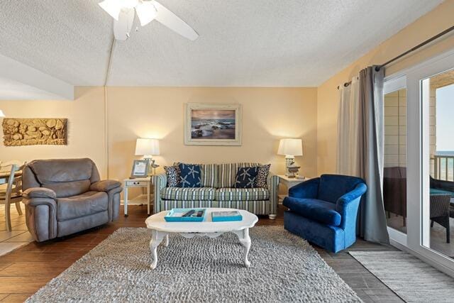 living room with ceiling fan, a textured ceiling, and dark wood-type flooring