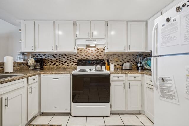 kitchen with white cabinets, white appliances, dark stone countertops, and tasteful backsplash