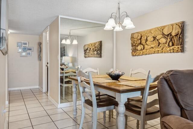 dining area with an inviting chandelier, a textured ceiling, and light tile patterned floors