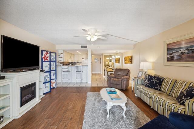 living room with ceiling fan, hardwood / wood-style flooring, and a textured ceiling