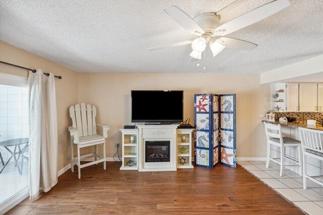 living room featuring ceiling fan, hardwood / wood-style flooring, and a textured ceiling