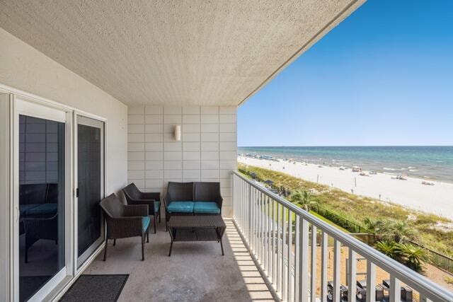 balcony featuring a water view and a beach view