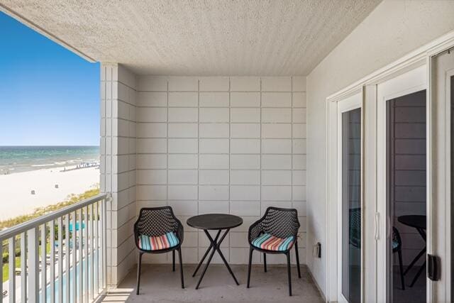 balcony featuring a beach view and a water view