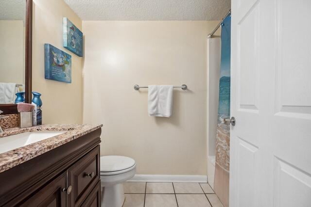 full bathroom with shower / bath combo with shower curtain, vanity, a textured ceiling, toilet, and tile patterned floors