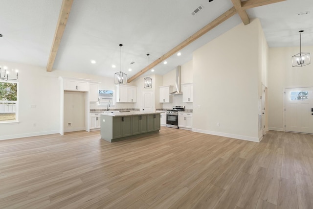 kitchen featuring wall chimney exhaust hood, stainless steel range, a kitchen island, and hanging light fixtures