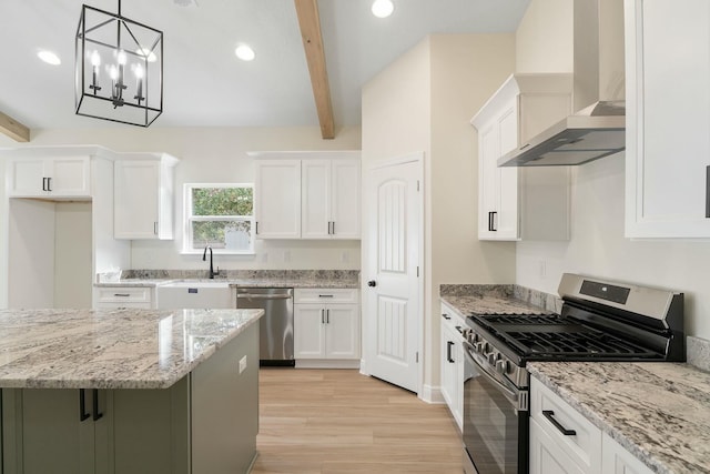 kitchen featuring white cabinets, hanging light fixtures, wall chimney exhaust hood, beam ceiling, and stainless steel appliances