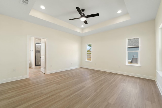 spare room featuring light hardwood / wood-style floors, ceiling fan, and a tray ceiling