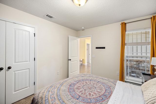 carpeted bedroom with a textured ceiling and a closet