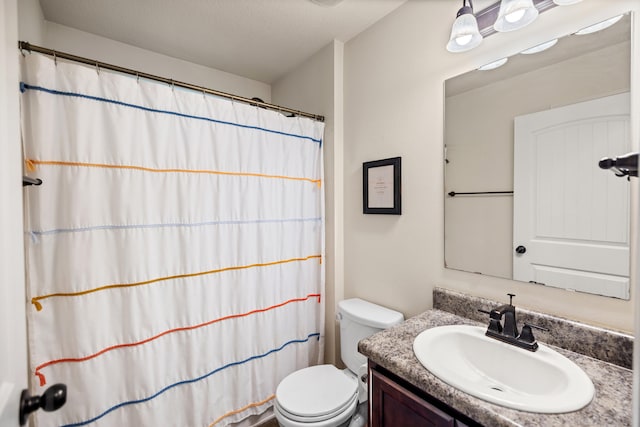 bathroom with vanity, toilet, and a textured ceiling