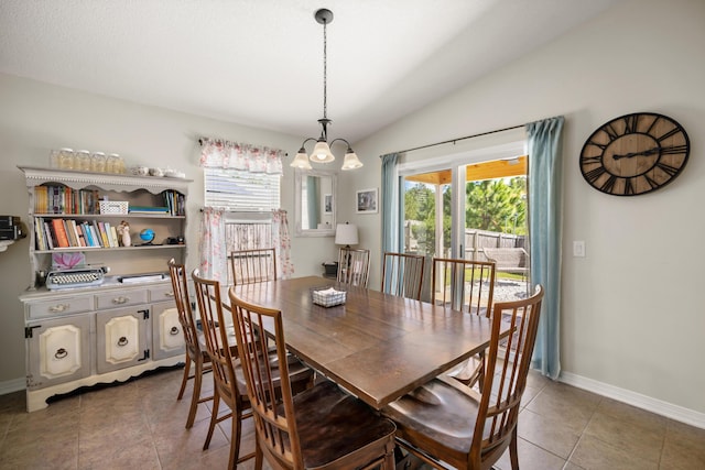 dining room with an inviting chandelier, vaulted ceiling, and dark tile patterned floors