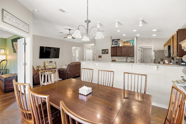 tiled dining area with ceiling fan with notable chandelier