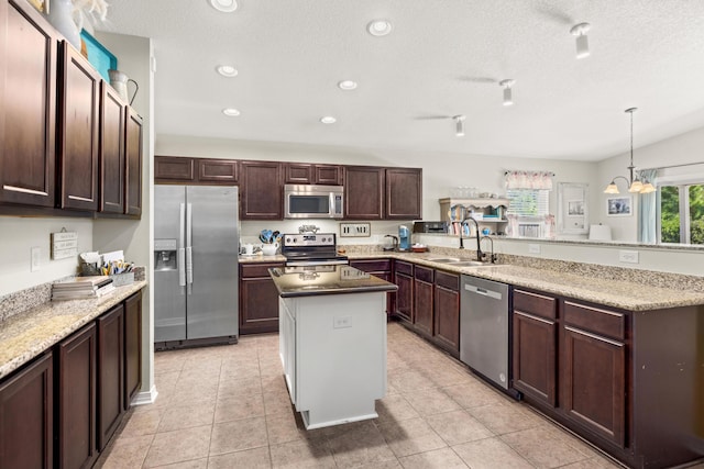 kitchen with sink, stainless steel appliances, a center island, decorative light fixtures, and kitchen peninsula