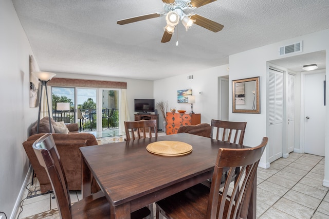 dining area featuring a textured ceiling, visible vents, a ceiling fan, and baseboards