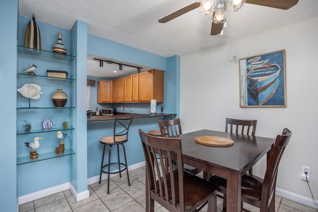 tiled dining space with ceiling fan, a textured ceiling, and track lighting