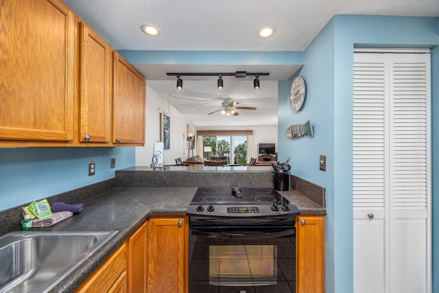 kitchen featuring rail lighting, ceiling fan, electric range, sink, and a textured ceiling